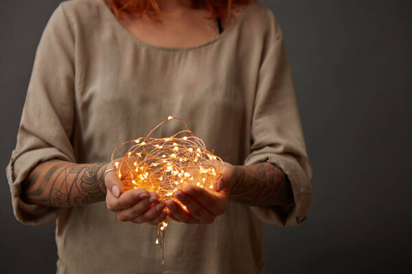 женщина держит электрические гирлянды рождественские огни на темном фоне
