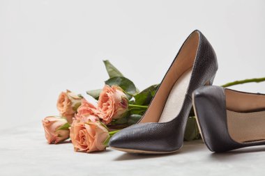 zarif siyah kadın ayakkabı ve beyaz arka plan üzerinde pembe gül buketi