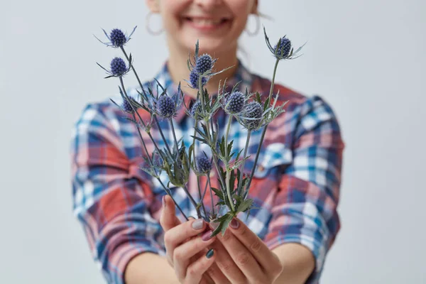 母の日の概念 灰色の背景の上 Eringium の新鮮な花の花束を保持している若い女性の写真をトリミング — ストック写真