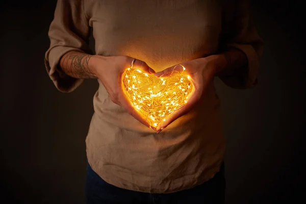 妇女在心脏形状的电子花环 圣诞节灯在黑暗的背景 — 图库照片