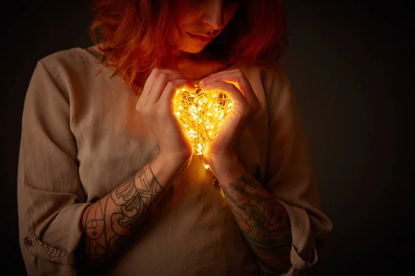 妇女在心脏形状的电子花环 圣诞节灯在黑暗的背景 — 图库照片