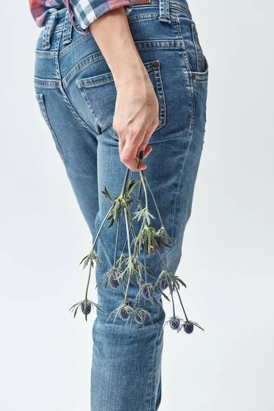 青いヒゴタイサイコ属の花 母の日の概念の枝を保持しているジーンズでスリムな若い女性の背面図 — ストック写真