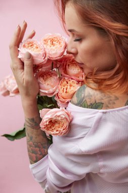 Kızıl saçlı genç kadın bir buket pembe güller, Sevgililer günü kavramı koklama