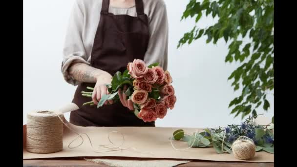 Eringium ピンクのバラの花束を作るエプロンの女性のビデオ 花ショップ コンセプトです ストップ モーション — ストック動画