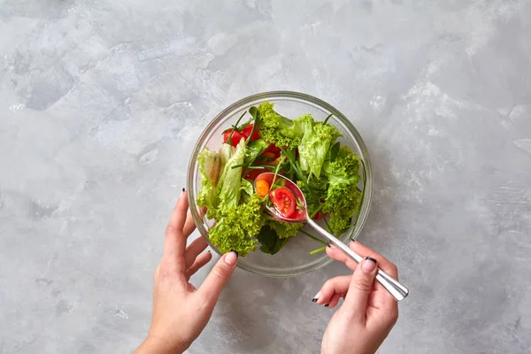灰色のテーブルの上の野菜のヘルシーなサラダを食べる女性の手 — ストック写真