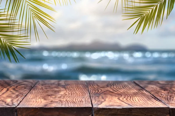Holztisch Auf Dem Hintergrund Des Verschwommenen Sonnenuntergangs Meer Und Palmenblätter — Stockfoto