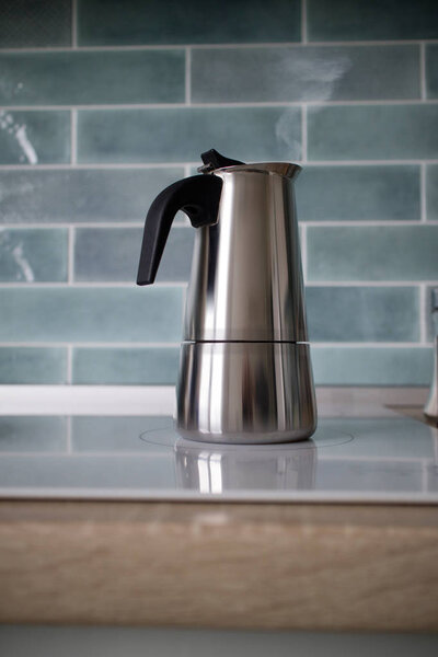 modern stainless geyser coffee maker in kitchen on the induction panel 