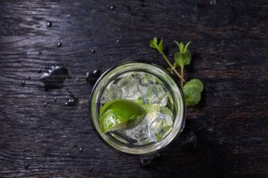 Buzlu Mojito kokteyl bardak ve malzemeler, kireç, buz ve nane yaprakları siyah arka plan üzerine, soğuk yaz içeceği 