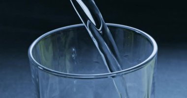 temiz su bardağına mavi zemin üzerine dökülür varlık