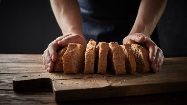 adam tutarak taze ekmek ahşap masa, ağır çekim dilimlenmiş. 