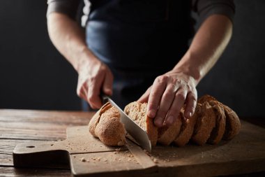 adam ahşap masa, ağır çekim taze ekmek dilimleme 