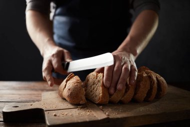 adam ahşap masa, ağır çekim taze ekmek dilimleme 