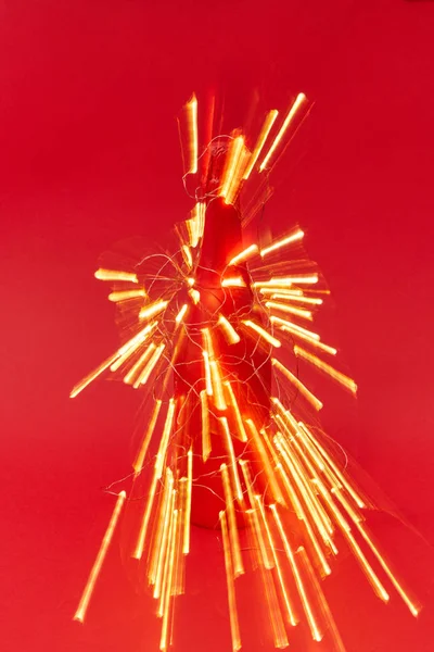 火焰喷射器从装饰过的酒瓶上闪烁着圣诞彩灯的痕迹 红色背景 有复制空间 贺年卡 — 图库照片