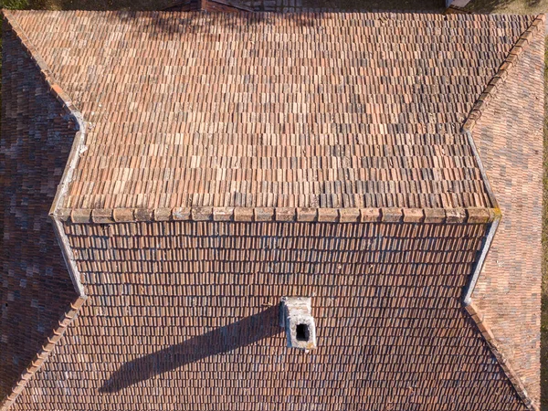 夏の日に日当たりの良いから高い煙突とハード影と家の上に古いタイルの屋根 ドローンからの空中展望 — ストック写真