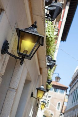 İtalyan caddesinde parlak sarı ışık saçan eski moda fenerlerle dolu tarihi binalar..