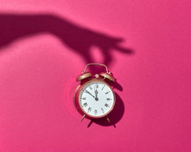 Retro Cooper çalar saati, arka planda pembe bir kadının elinden çıkan sert gölgeler, boşluğu kopyala.