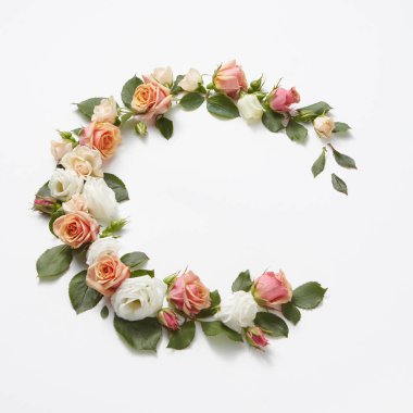 Açık gri arka planda yeşil yapraklı güzel gül çiçeklerinden köşe çelengi şeklinde dekorasyon, kopyalama alanı. Doğum günü için tebrik kartı..