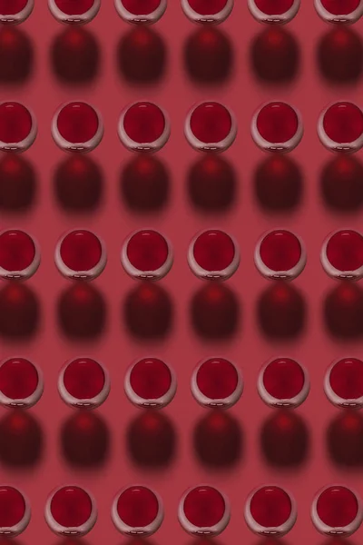 赤ワインアルコールを含むグラスからの幾何学的なパターンは ハードシャドウと赤の背景に飲みます トップ表示 — ストック写真