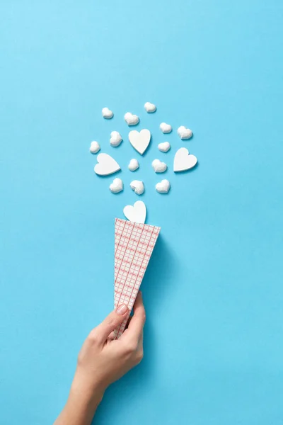 薄い青の背景とコピースペースに女性の手の中にアイスクリームデザートとして小さな石膏の心の紙コーンと創造的な休日のカード バレンタインデーグリーティングカード — ストック写真