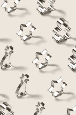 Dikey olarak ayakta duran paslanmaz çelik kesiciler ev yapımı yıldızlı kurabiyeler ve zencefilli çörekler için yumuşak gölgeli açık gri bir zemin üzerinde.