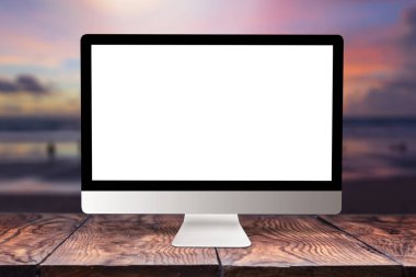 Empty white mock-up computer display on a wooden table against blurred sea sunset background with bokeh, copy space. Working remotely concept. clipart