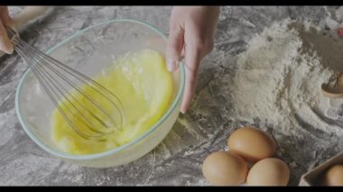 Kadın çırpılmış yumurta sarısı çırpıyor, hamur yoğurmaya hazırlanıyor.