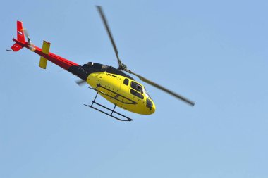 Küçük sarı helikopter gökyüzünde uçar.