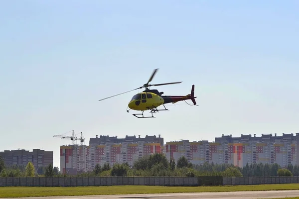 Małe żółte helikopter leci na niebie nad miastem — Zdjęcie stockowe