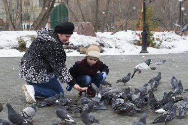 Küçük çocuk annesi ile parktaki güvercinler kışın beslenir.