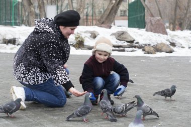Güvercinler wint parkta küçük çocuk annesi ile beslenir