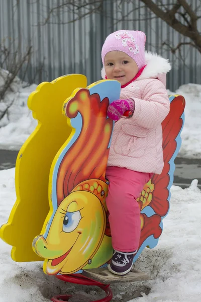 The little girl plays in the winter on the playground. — Stock Photo, Image