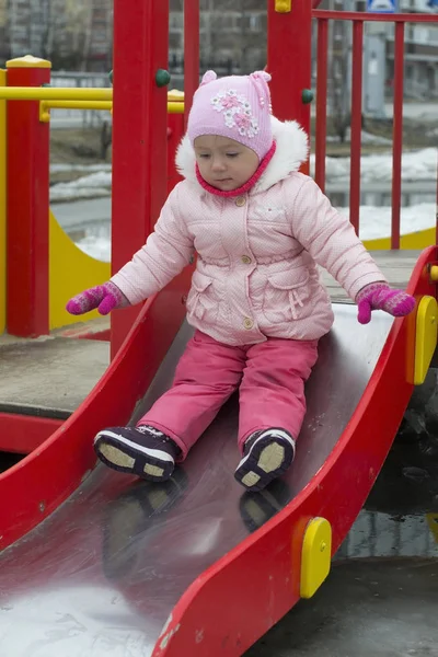 Маленькая девочка играет зимой на детской площадке . — стоковое фото