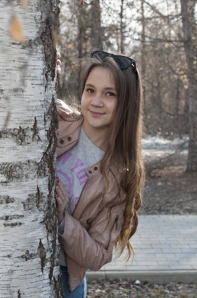 La jeune femme se tient près d'un arbre dans le parc . — Photo