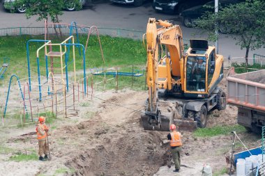 Tyumen, Rusya, 25 Mayıs 2000: Bir yerleşim yerinin avlusunda onarım çalışmaları. Kazıcı su boruları döşemek için bir çukur kazıyor..
