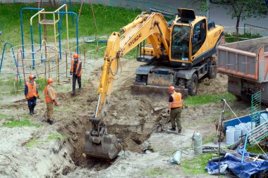 Tyumen, Rusya, 25 Mayıs 2000: Bir yerleşim yerinin avlusunda onarım çalışmaları. Kazıcı su boruları döşemek için bir çukur kazıyor..