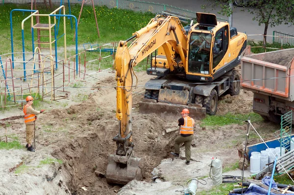 2000年5月25日 俄罗斯蒂门 在一座住宅楼的院子里进行维修 挖掘机正在挖一条壕沟来敷设水管 图库照片