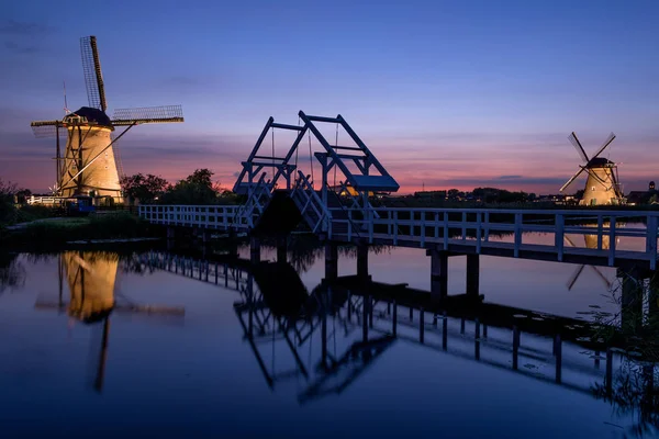 Mulini a vento illuminati, un ponte e un canale al tramonto — Foto Stock