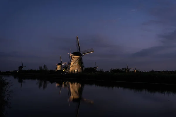 Moinhos de vento ao longo da água em Kinderdijk no crepúsculo — Fotografia de Stock