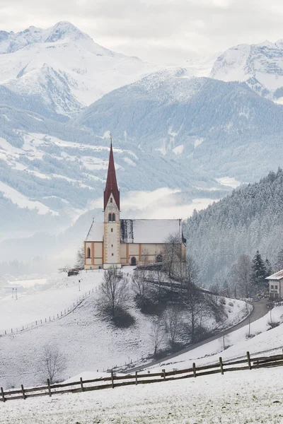 冬のオーストリアのアルプスの山背景を持つ教会 — ストック写真