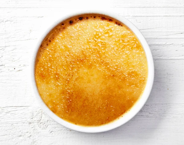 Bowl of creme brule on white wooden table — Stock Photo, Image