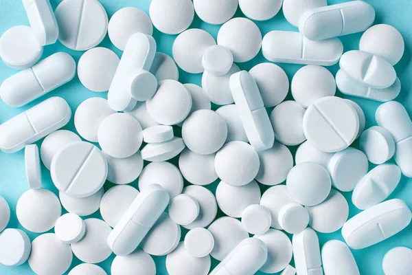 Várias pílulas brancas no fundo azul — Fotografia de Stock