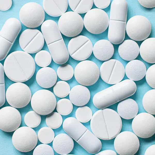 Białe tabletki na niebieskim tle — Zdjęcie stockowe