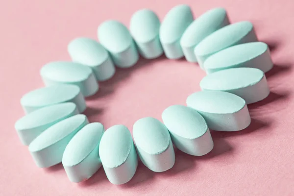 Niebieskie tabletki na różowym tle — Zdjęcie stockowe
