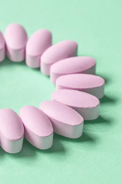 Růžové pilulky na zeleném pozadí — Stock fotografie