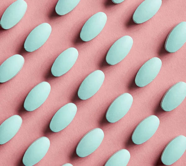 Pílulas verdes em fundo rosa — Fotografia de Stock
