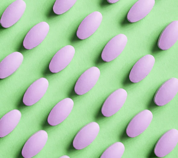 Purple pills on green background — Stock Photo, Image