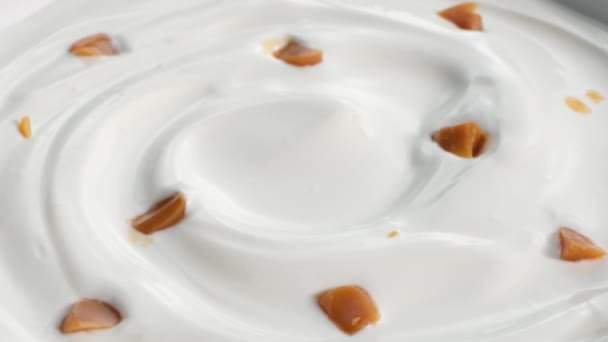 Roterande Gräddfil Eller Grekisk Yoghurt Virvel Med Karamell Bitar — Stockvideo