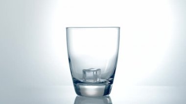 Buz küpleri cama düşüyor, ağır çekimde.