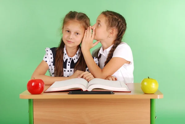 Dvě školy dívka sdílení tajemství sedí u stolu z knihy — Stock fotografie
