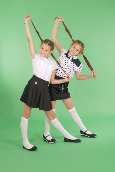 Twee schoolmeisjes speelt met gevlochten haren. — Stockfoto